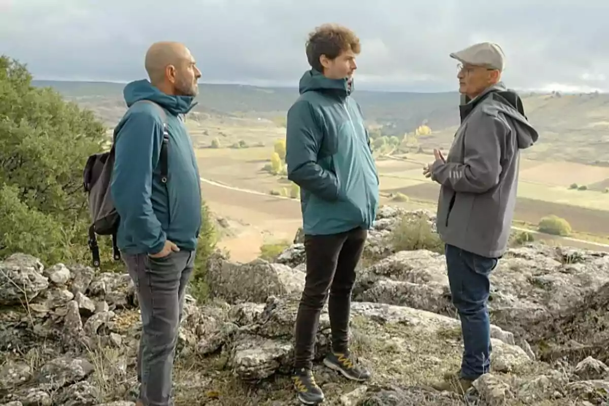 Eloi Vila al costat de Miki Núñez i una altra persona en un paisatge rural amb turons i camps al fons a Quanta Guerra! Eloi Vila al costat de Miki Núñez i una altra persona en un paisatge rural amb turons i camps al fons a Quanta Guerra!