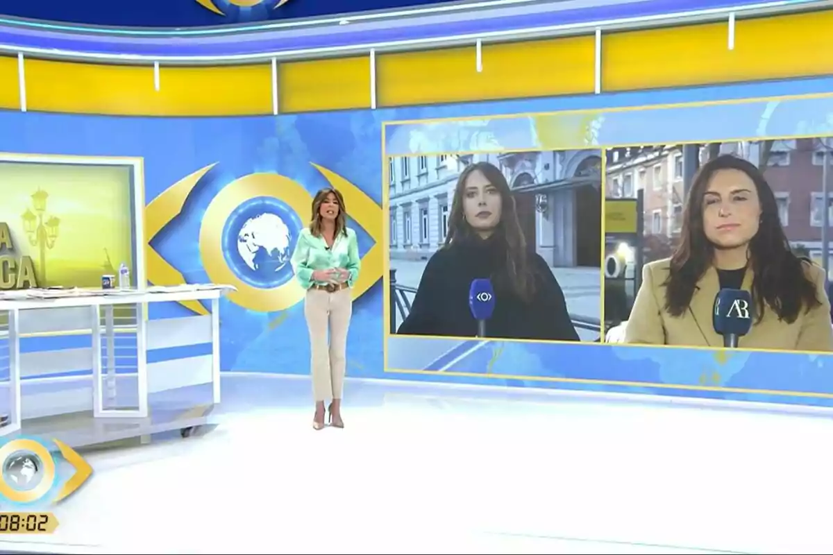 La Mirada Crítica con Ana Terradillos de pie y dos reporteras en pantallas grandes detrás de ella, cada una sosteniendo un micrófono. La Mirada Crítica con Ana Terradillos de pie y dos reporteras en pantallas grandes detrás de ella, cada una sosteniendo un micrófono.
