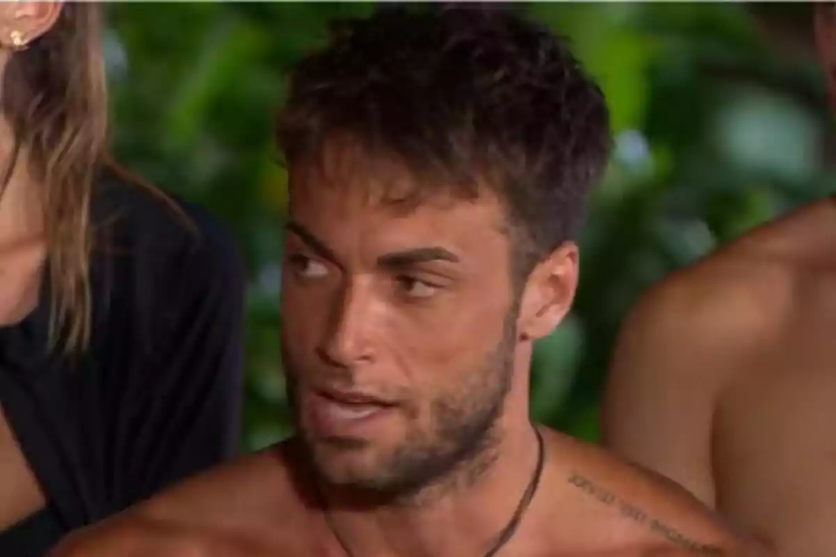Montoya con barba y cabello oscuro mira hacia un lado en un entorno al aire libre con vegetación de fondo en Supervivientes.