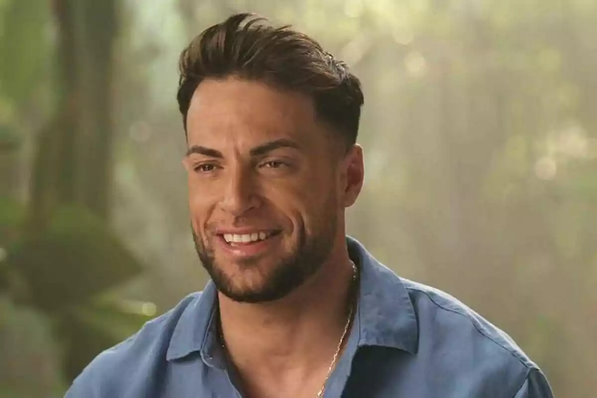 Montoya sonriente con barba y cabello oscuro lleva una camisa azul en un entorno natural iluminado en Supervivientes. Montoya sonriente con barba y cabello oscuro lleva una camisa azul en un entorno natural iluminado en Supervivientes.