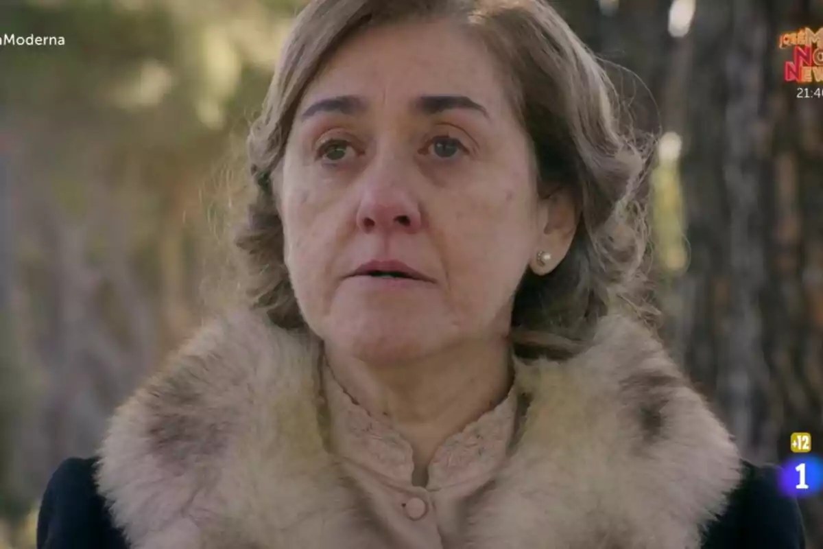 María José Parra con expresión seria y ojos llorosos, vestida con un abrigo de piel, en un entorno al aire libre en La Moderna. María José Parra con expresión seria y ojos llorosos, vestida con un abrigo de piel, en un entorno al aire libre en La Moderna.