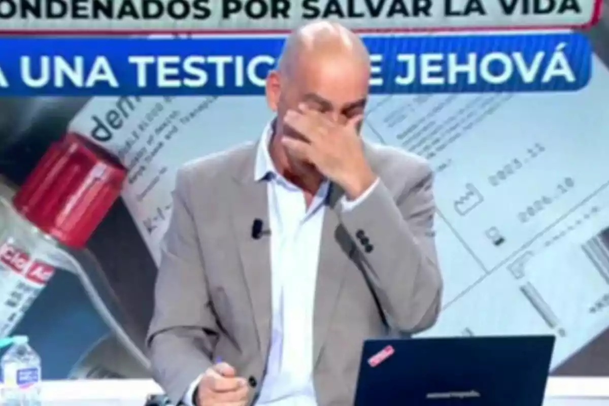 Nacho Abad con traje claro se cubre el rostro con la mano por sus lágrimas en En Boca de Todos mientras está sentado frente a una computadora portátil, con un fondo que muestra un frasco de medicamento y un texto que dice Nacho Abad con traje claro se cubre el rostro con la mano por sus lágrimas en En Boca de Todos mientras está sentado frente a una computadora portátil, con un fondo que muestra un frasco de medicamento y un texto que dice