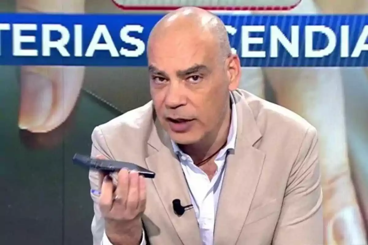 Nacho Abad con traje claro sostiene un objeto en la mano mientras habla en En Boca de Todos. Nacho Abad con traje claro sostiene un objeto en la mano mientras habla en En Boca de Todos.