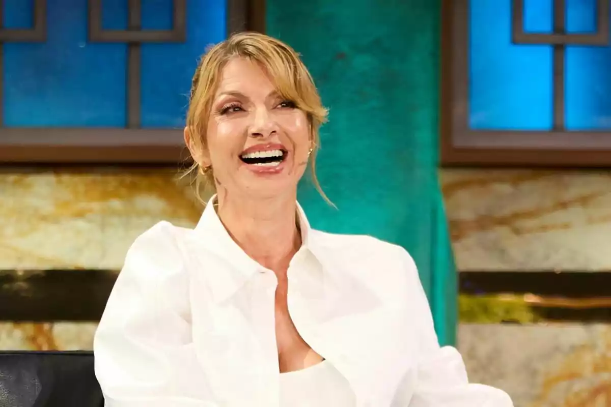 Najwa Nimri sonriente con una camisa blanca, sentada frente a un fondo colorido en La Revuelta. Najwa Nimri sonriente con una camisa blanca, sentada frente a un fondo colorido en La Revuelta.