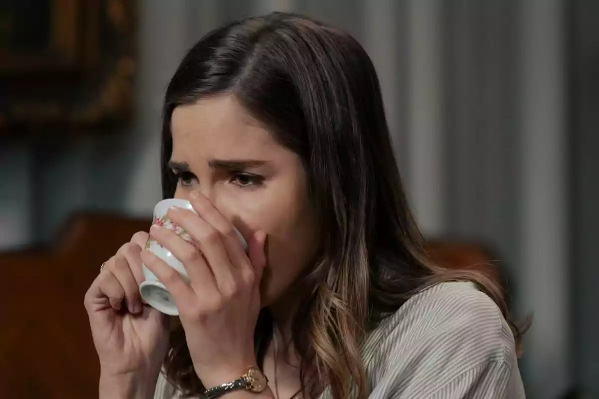 Fotografía de Natalia Sánchez con cabello castaño claro está bebiendo de una taza de porcelana decorada con flores en Sueños de Libertad. Fotografía de Natalia Sánchez con cabello castaño claro está bebiendo de una taza de porcelana decorada con flores en Sueños de Libertad.