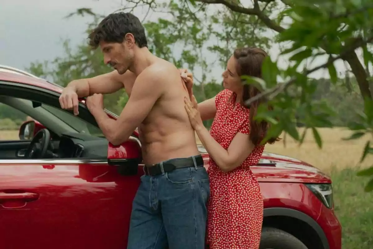 Andrés Velencoso sense camisa es recolza en un cotxe vermell mentre una Natalia Sánchez en vestit vermell li aplica alguna cosa a l'esquena en un entorn exterior a Retorn a les Sabines. Andrés Velencoso sense camisa es recolza en un cotxe vermell mentre una Natalia Sánchez en vestit vermell li aplica alguna cosa a l'esquena en un entorn exterior a Retorn a les Sabines.