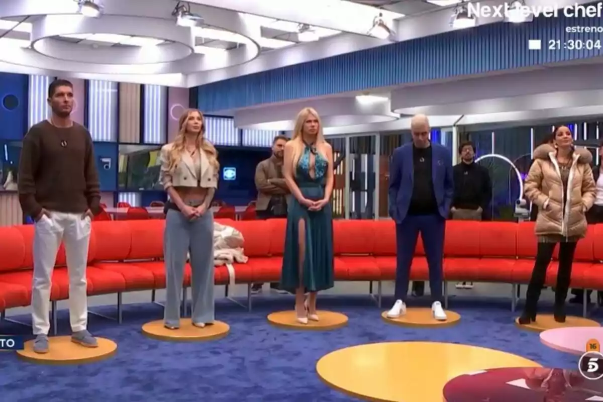 Àlex Ghita, Vanessa Bouza, Ana Herminia, Javi Mouzo i Romina Malaspina de peu a GH DÚO amb un sofà vermell i un fons modern.