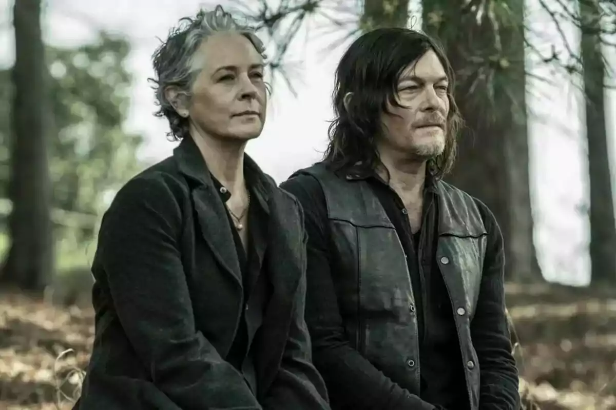Fotografía de Norman Reedus y Melissa McBride sentadas en un bosque, una mujer de cabello corto y canoso y un hombre de cabello largo y oscuro en The Walking Dead: Daryl Dixon Fotografía de Norman Reedus y Melissa McBride sentadas en un bosque, una mujer de cabello corto y canoso y un hombre de cabello largo y oscuro en The Walking Dead: Daryl Dixon