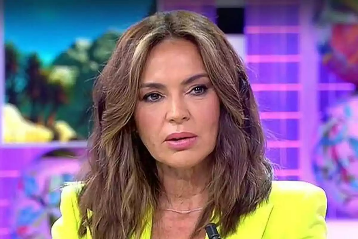 Olga Moreno con cabello castaño y expresión seria en Fiesta con fondo colorido.