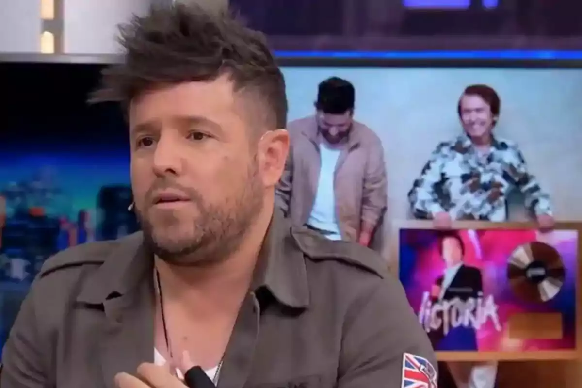 Pablo López con barba y cabello oscuro está hablando en un El Hormiguero, con una imagen de fondo que muestra al propio Pablo López junto a Raphael sosteniendo un cuadro. Pablo López con barba y cabello oscuro está hablando en un El Hormiguero, con una imagen de fondo que muestra al propio Pablo López junto a Raphael sosteniendo un cuadro.