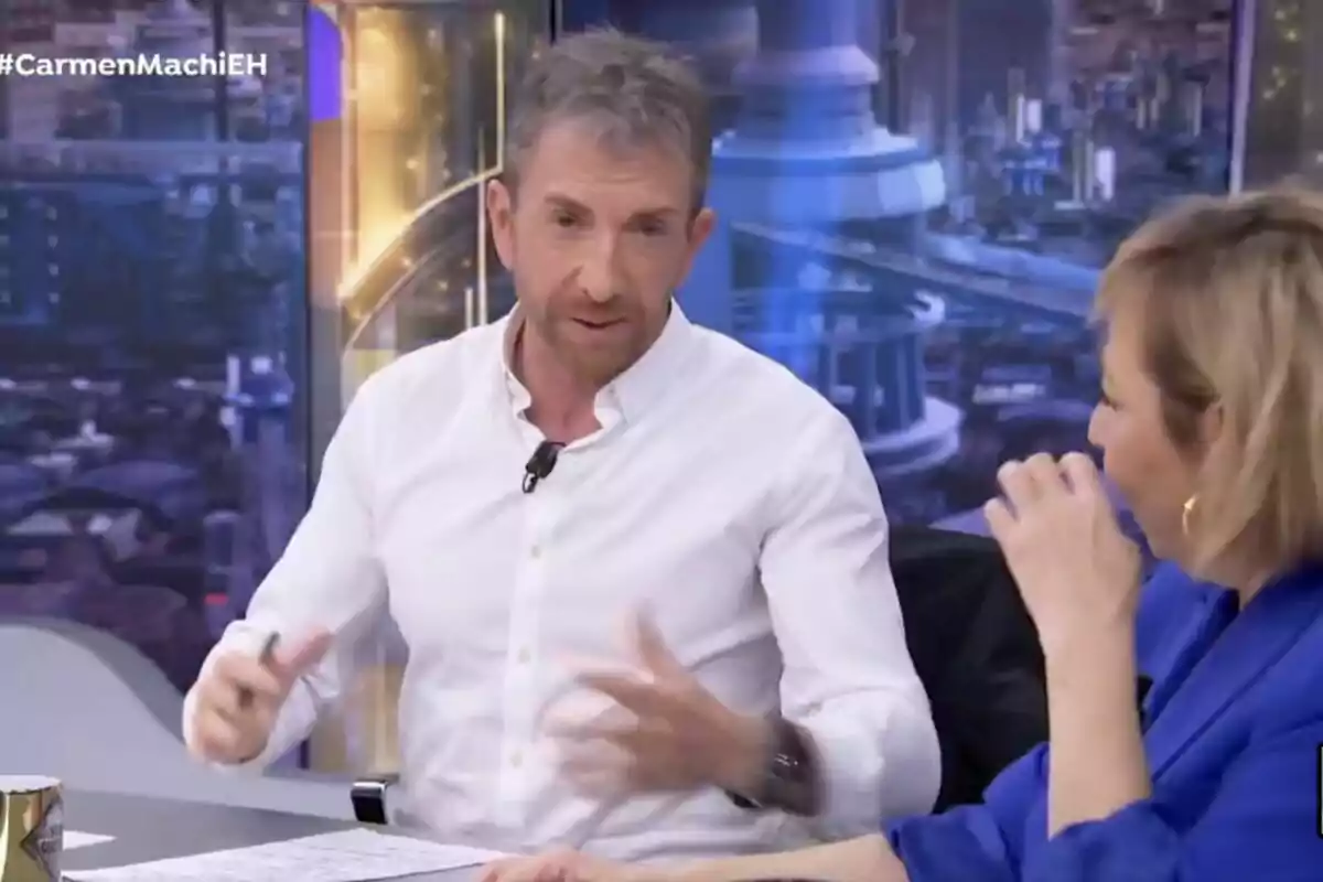 Pablo Motos y Carmen Machi conversan en El Hormiguero con un fondo urbano iluminado. Pablo Motos y Carmen Machi conversan en El Hormiguero con un fondo urbano iluminado.