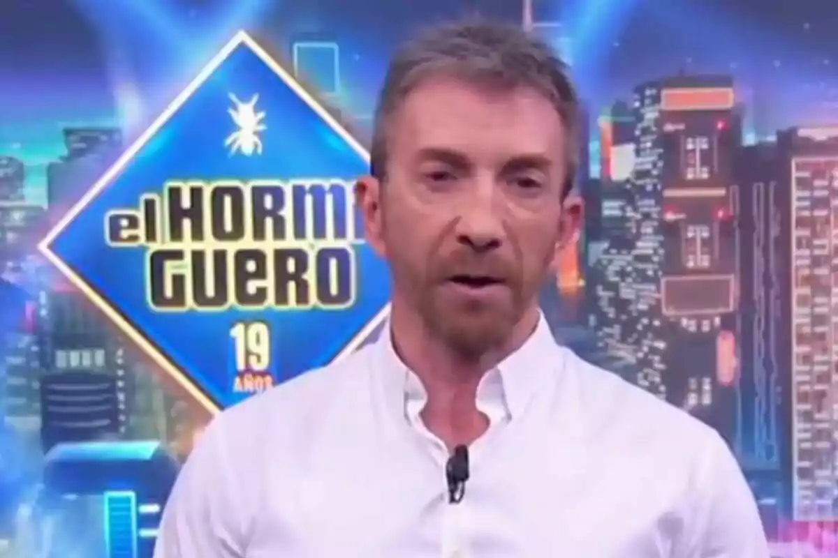 Pablo Motos con camisa blanca está frente a un fondo colorido con el logotipo de Pablo Motos con camisa blanca está frente a un fondo colorido con el logotipo de