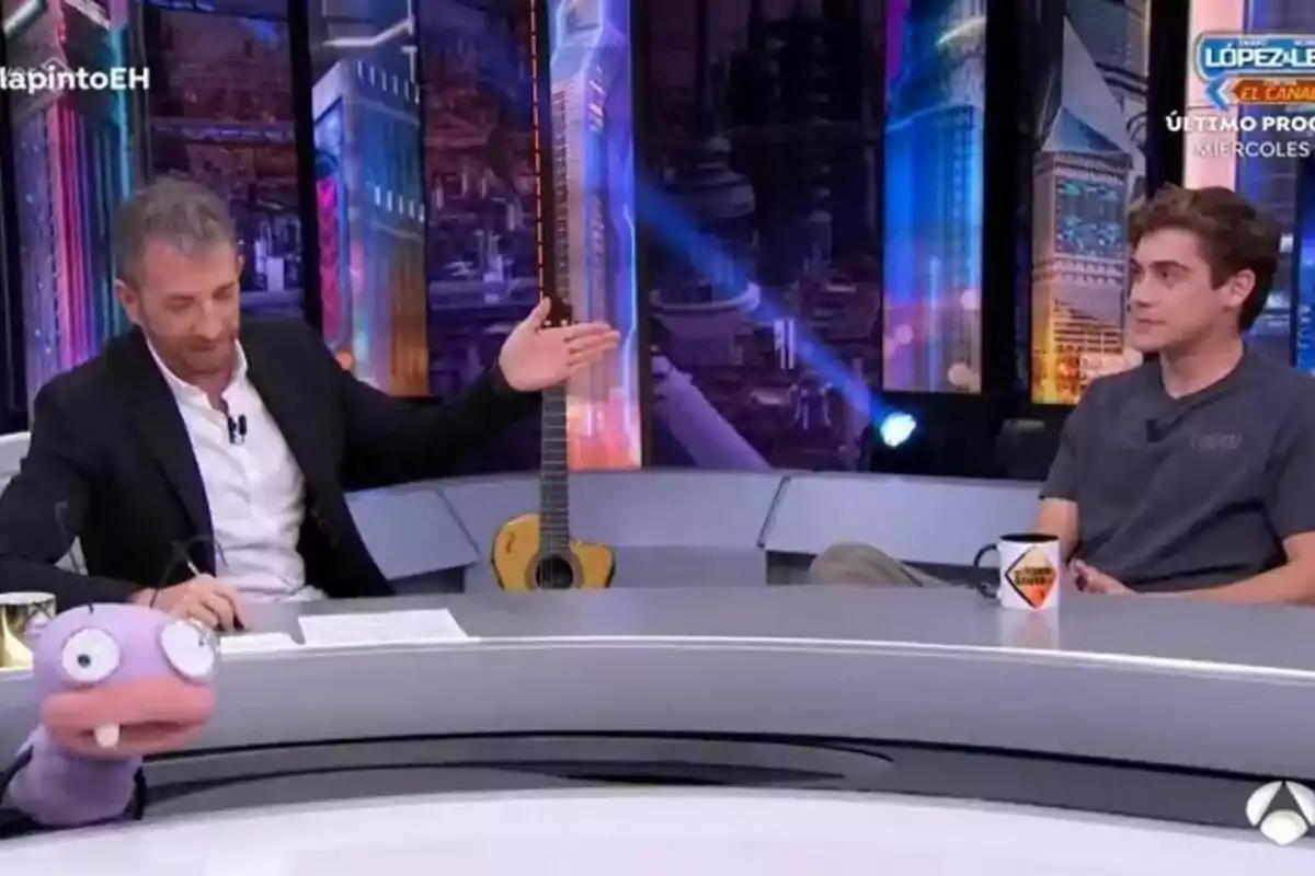 Pablo Motos está sentado en el plató de El Hormiguero junto a Franco Colapinto, con una guitarra de fondo y una marioneta en primer plano. Pablo Motos está sentado en el plató de El Hormiguero junto a Franco Colapinto, con una guitarra de fondo y una marioneta en primer plano.