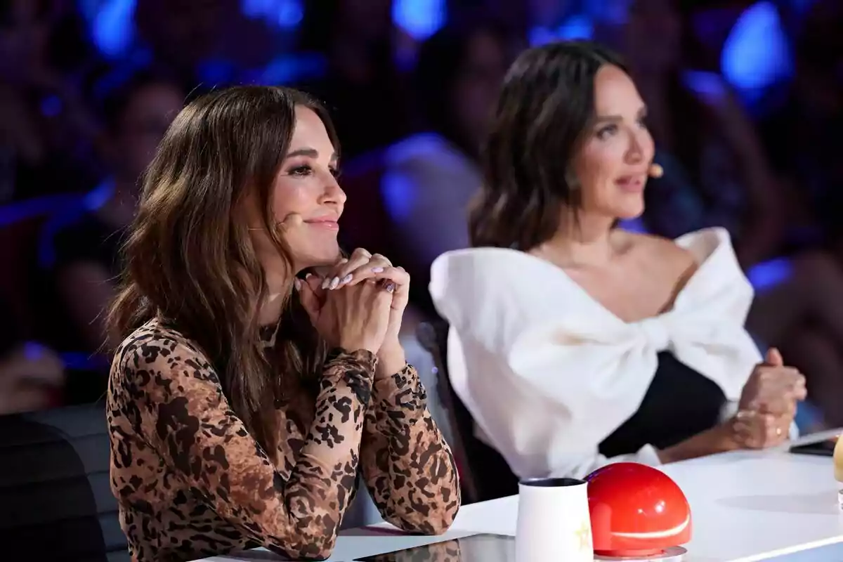 Paula Echevarría amb Tamara Falcó assegudes a la taula de Got Talent, una amb un vestit d'estampat animal i l'altra amb un vestit blanc amb un gran llaç, totes dues amb micròfons a l'orella i una llum blava de fons. Paula Echevarría amb Tamara Falcó assegudes a la taula de Got Talent, una amb un vestit d'estampat animal i l'altra amb un vestit blanc amb un gran llaç, totes dues amb micròfons a l'orella i una llum blava de fons.