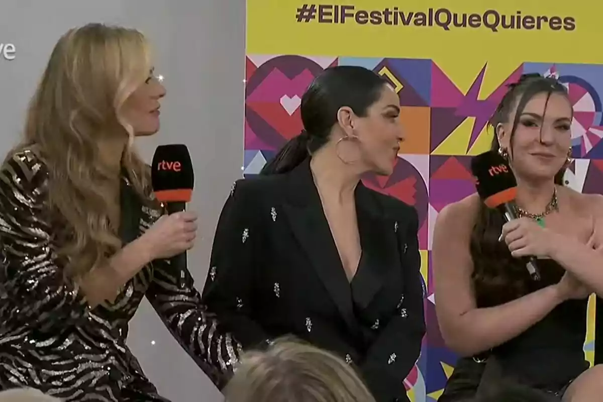 Paula Vázquez, Ruth Lorenzo i Inés Hernand sostenen micròfons de RTVE mentre conversen en un esdeveniment amb un fons colorit que inclou el hashtag #ElFestivalQueVols del Benidorm Fest. Paula Vázquez, Ruth Lorenzo i Inés Hernand sostenen micròfons de RTVE mentre conversen en un esdeveniment amb un fons colorit que inclou el hashtag #ElFestivalQueVols del Benidorm Fest.