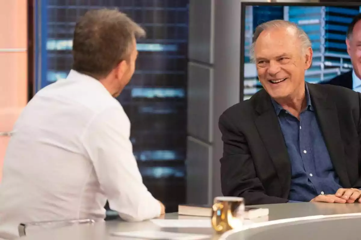 Pablo Motos y Pedro Piqueras conversan en El Hormiguero, uno de ellos sonríe mientras el otro está de espaldas. Pablo Motos y Pedro Piqueras conversan en El Hormiguero, uno de ellos sonríe mientras el otro está de espaldas.