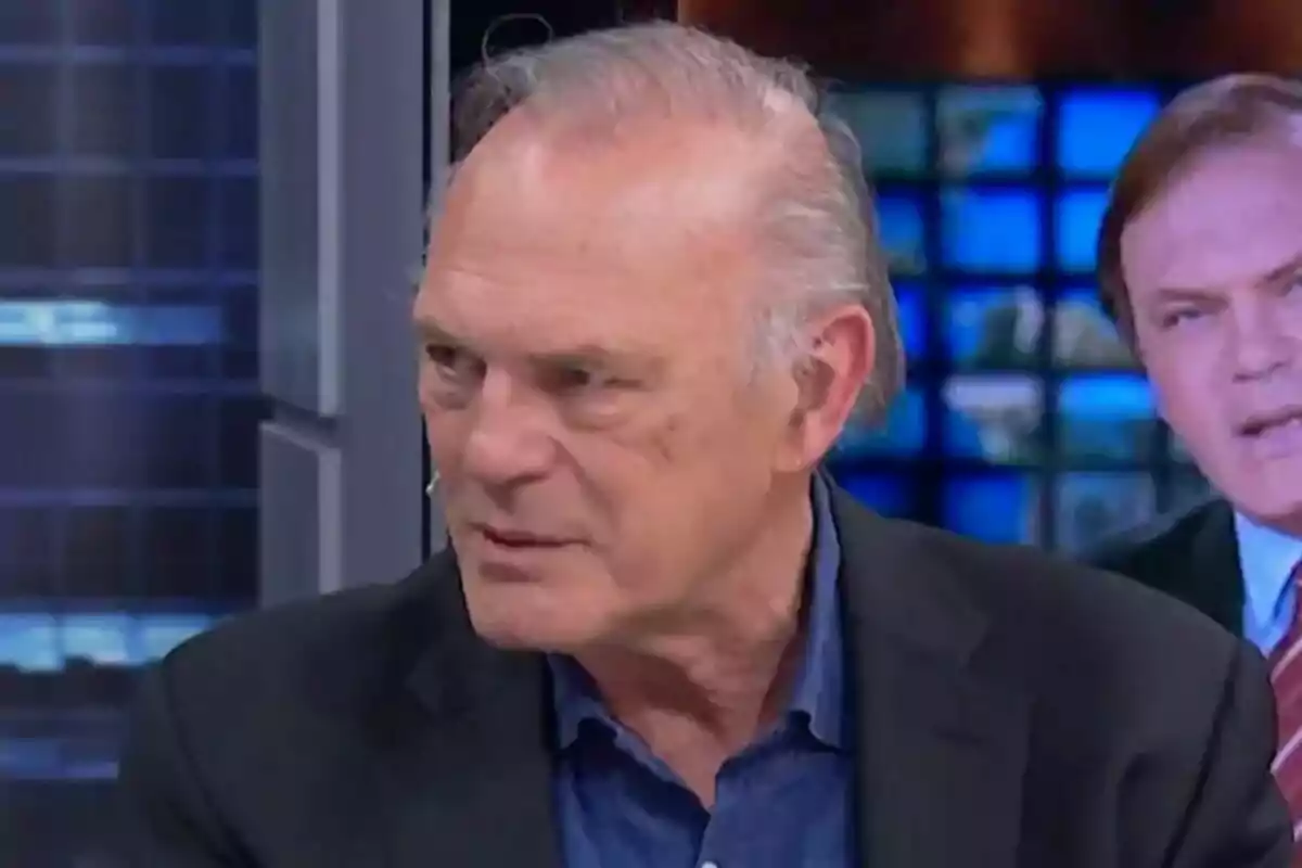 Pedro Piqueras con cabello canoso y expresión seria está en El Hormiguero con pantallas de fondo.