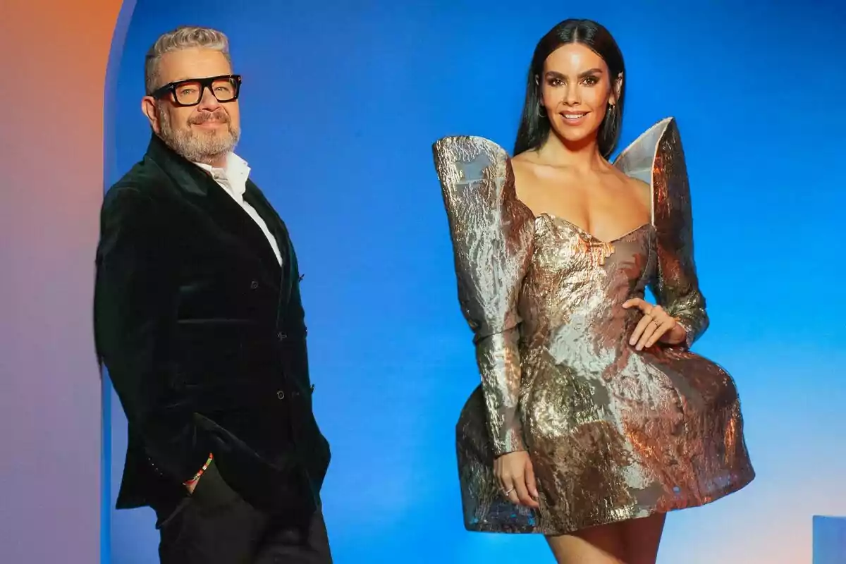 Alberto Chicote y Cristina Pedroche posan frente a un fondo azul, una de ellas lleva un vestido metálico con volúmenes y la otra un traje oscuro con gafas. Alberto Chicote y Cristina Pedroche posan frente a un fondo azul, una de ellas lleva un vestido metálico con volúmenes y la otra un traje oscuro con gafas.