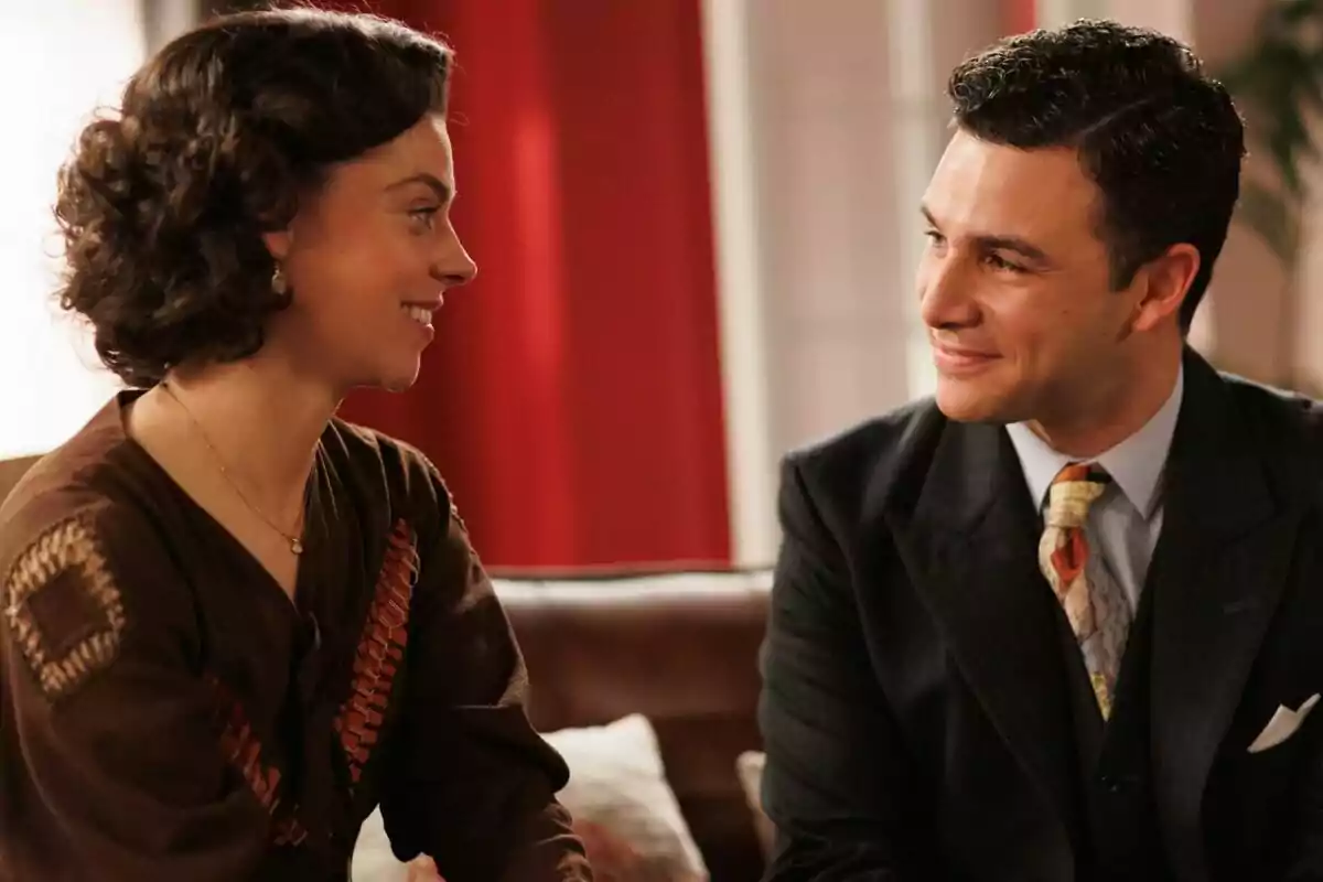 Clara Alvarado y Pepe Nufrio vestidos de manera elegante se miran y sonríen mientras están sentados en un sofá en La Moderna. Clara Alvarado y Pepe Nufrio vestidos de manera elegante se miran y sonríen mientras están sentados en un sofá en La Moderna.