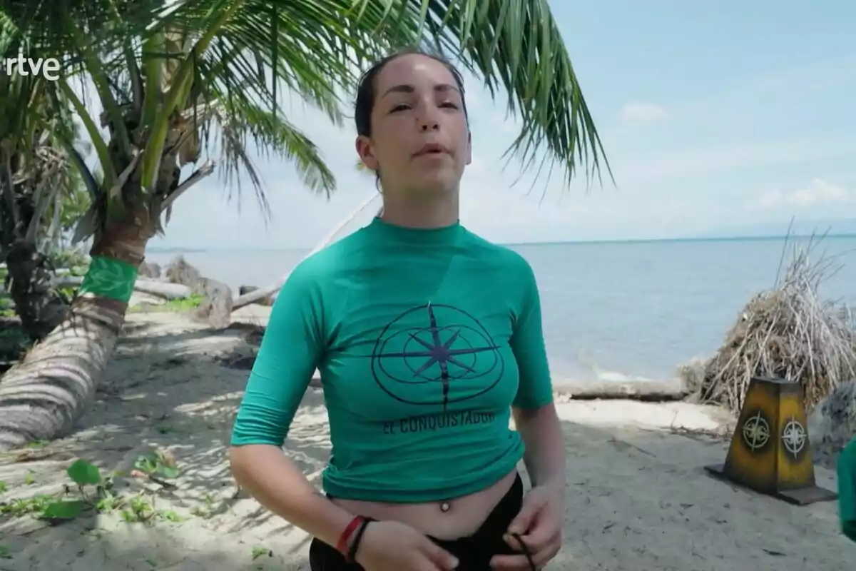 Anita Williams con camiseta verde en una playa con palmeras y el mar de fondo. Anita Williams con camiseta verde en una playa con palmeras y el mar de fondo.