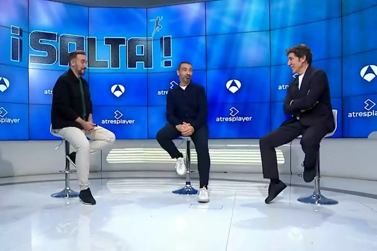 Carlos F. Recio, Jonathan Ruiz i Manel Fuentes estan asseguts en tamborets en un plató de televisió amb un fons blau que mostra el logotip d'Antena 3 i Atresplayer i la paraula Carlos F. Recio, Jonathan Ruiz i Manel Fuentes estan asseguts en tamborets en un plató de televisió amb un fons blau que mostra el logotip d'Antena 3 i Atresplayer i la paraula