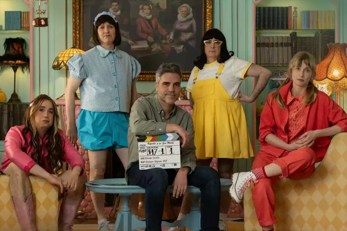 Ingrid García-Jonsson, Carlos Areces, Aníbal Gómez, Joaquín Reyes y Ernesto Sevilla posan en un set de filmación con vestuario colorido y un fondo decorado con libros y lámparas vintage en Rafaela y su loco mundo. Ingrid García-Jonsson, Carlos Areces, Aníbal Gómez, Joaquín Reyes y Ernesto Sevilla posan en un set de filmación con vestuario colorido y un fondo decorado con libros y lámparas vintage en Rafaela y su loco mundo.