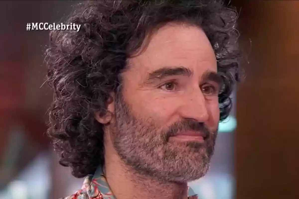 Raúl Gómez con barba y cabello rizado aparece en MasterChef Celebrity con el hashtag #MCCelebrity en la esquina superior izquierda. Raúl Gómez con barba y cabello rizado aparece en MasterChef Celebrity con el hashtag #MCCelebrity en la esquina superior izquierda.