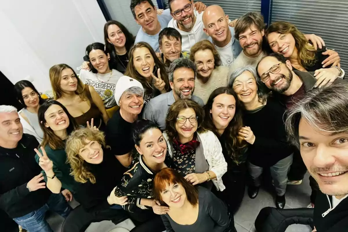 Un grupo de personas sonrientes formado por Alberto Caballero, Jordi Sánchez, Eva Isanta, Petra Martínez, Félix Gómez, Pablo Chiapella, Loles León, Nathalie Seseña, Nacho Guerreros, Raúl Peña, Mamen García, Margarita Asquerino, Rocío Marín, Carlos Chamarro, Ainhoa Larrañaga, Ana Arias, Elisabeth Larena y Carlota Boza posando juntas para una foto en un ambiente interior en el inicio del rodaje de La que se avecina.