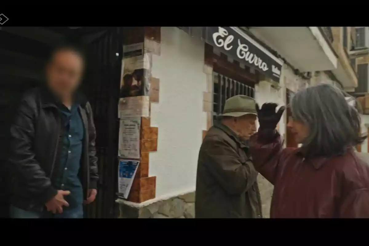 Personas de pie frente a un edificio con un cartel que dice 