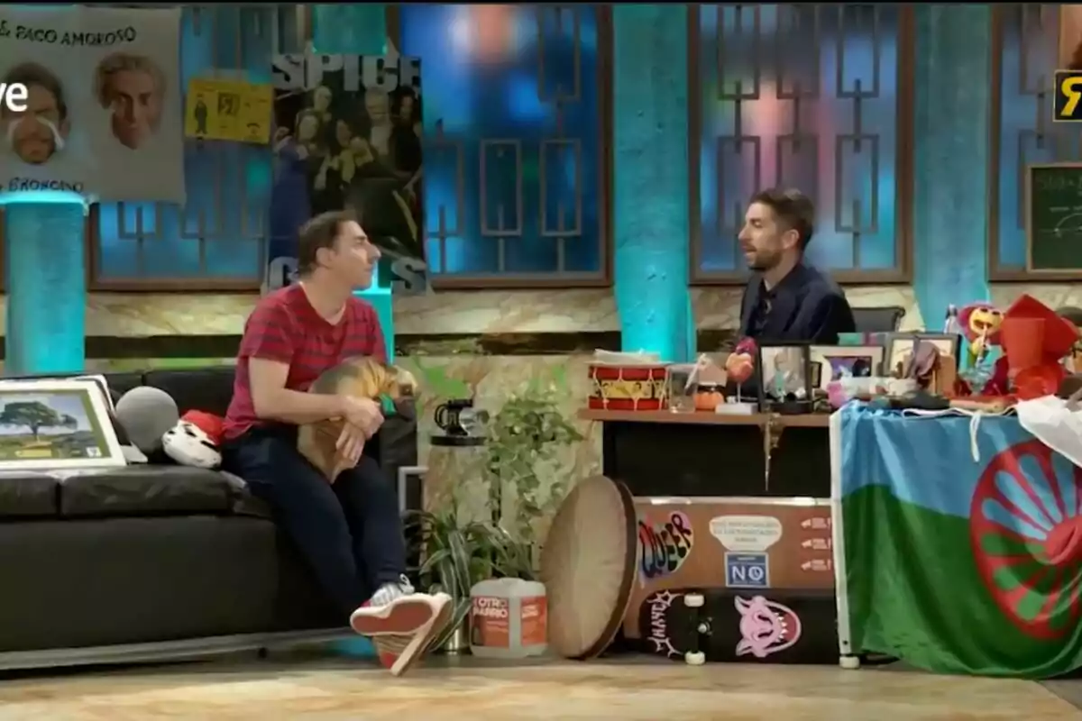 A la imatge s'observa un plató de televisió amb Jordi Roca i David Broncano conversant, un d'ells sosté un gos petit mentre estan envoltats de diversos objectes decoratius i cartells a les parets a 'La Revuelta'. A la imatge s'observa un plató de televisió amb Jordi Roca i David Broncano conversant, un d'ells sosté un gos petit mentre estan envoltats de diversos objectes decoratius i cartells a les parets a 'La Revuelta'.