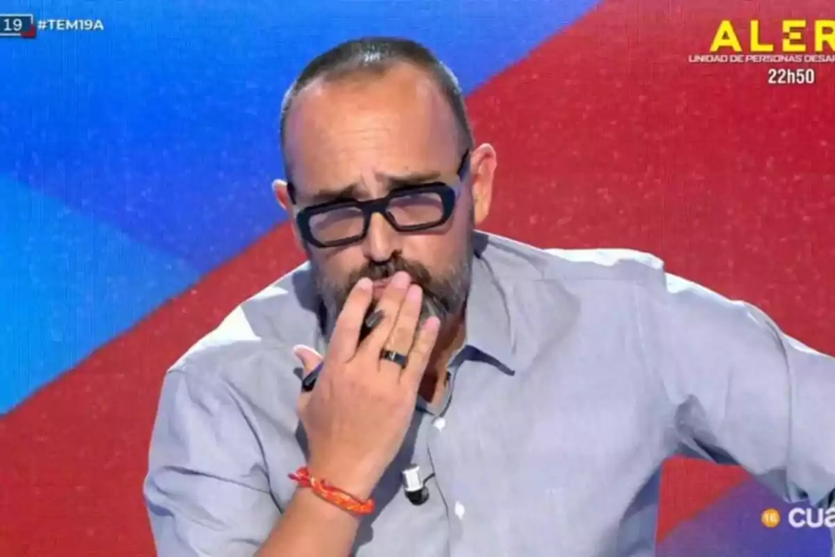 Captura de Risto Mejide con gafas y barba enTodo es Mentira, con fondo azul y rojo. Captura de Risto Mejide con gafas y barba enTodo es Mentira, con fondo azul y rojo.