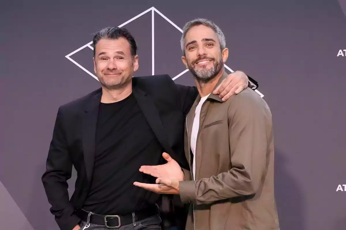 Iñaki López i Roberto Leal posant junts i somrient davant d'un fons gris amb un disseny geomètric blanc a la presentació de López i Leal contra el canal. Iñaki López i Roberto Leal posant junts i somrient davant d'un fons gris amb un disseny geomètric blanc a la presentació de López i Leal contra el canal.