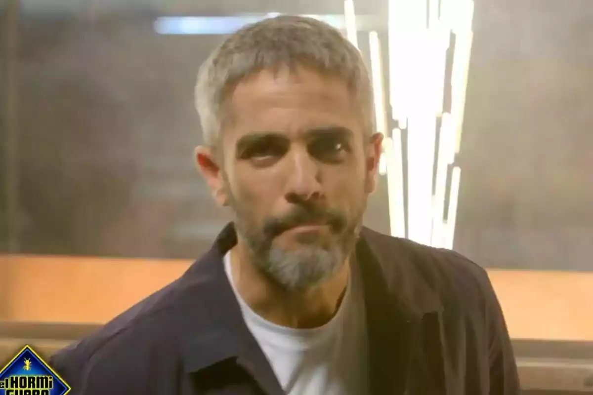 Roberto Leal de cabell curt i barba grisa amb expressió seriosa en un plató d’El Desafiament amb llums brillants al fons