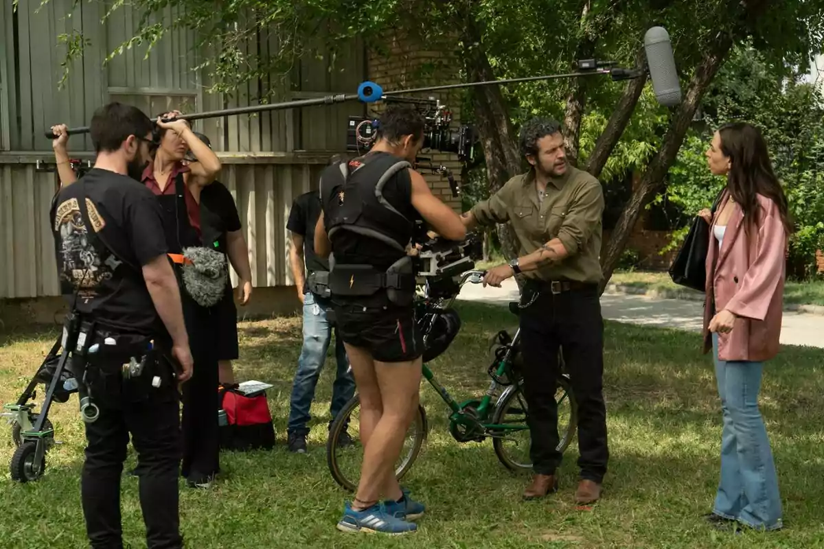 Equip de rodatge gravant una escena a l’aire lliure amb dos actors dialogant mentre l’equip tècnic sosté una càmera i un micròfon boom a la nova sèrie de comèdia ‘Sense Gluten’ de RTVE.