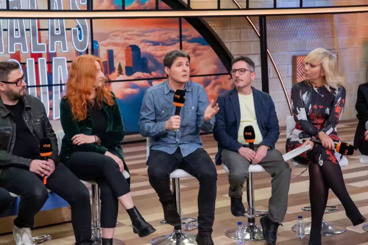 Jesús Cintora, Sergio Calderón, María Eizaguirre, Carmen González, David Lillo está sentado en un set de televisión, sosteniendo micrófonos de RTVE, mientras participan en una conversación o entrevista.