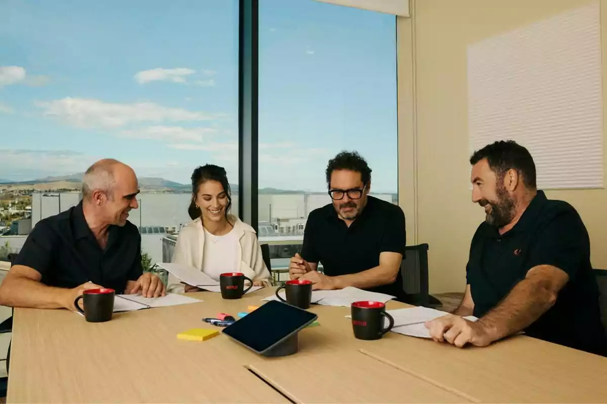 Fotografía de Fotografía de Aitor Gabilondo, Luis Tosar, Claudia Salas y Daniel Calparsoro sentadas alrededor de una mesa en una sala de reuniones con ventanas grandes y una vista panorámica, revisando documentos y sonriendo en el rodaje de Salvaje Fotografía de Fotografía de Aitor Gabilondo, Luis Tosar, Claudia Salas y Daniel Calparsoro sentadas alrededor de una mesa en una sala de reuniones con ventanas grandes y una vista panorámica, revisando documentos y sonriendo en el rodaje de Salvaje