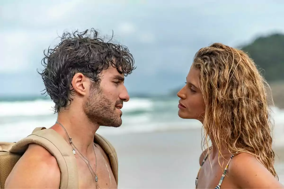 Una pareja se mira fijamente en la playa con el mar de fondo en la serie Cacao Una pareja se mira fijamente en la playa con el mar de fondo en la serie Cacao