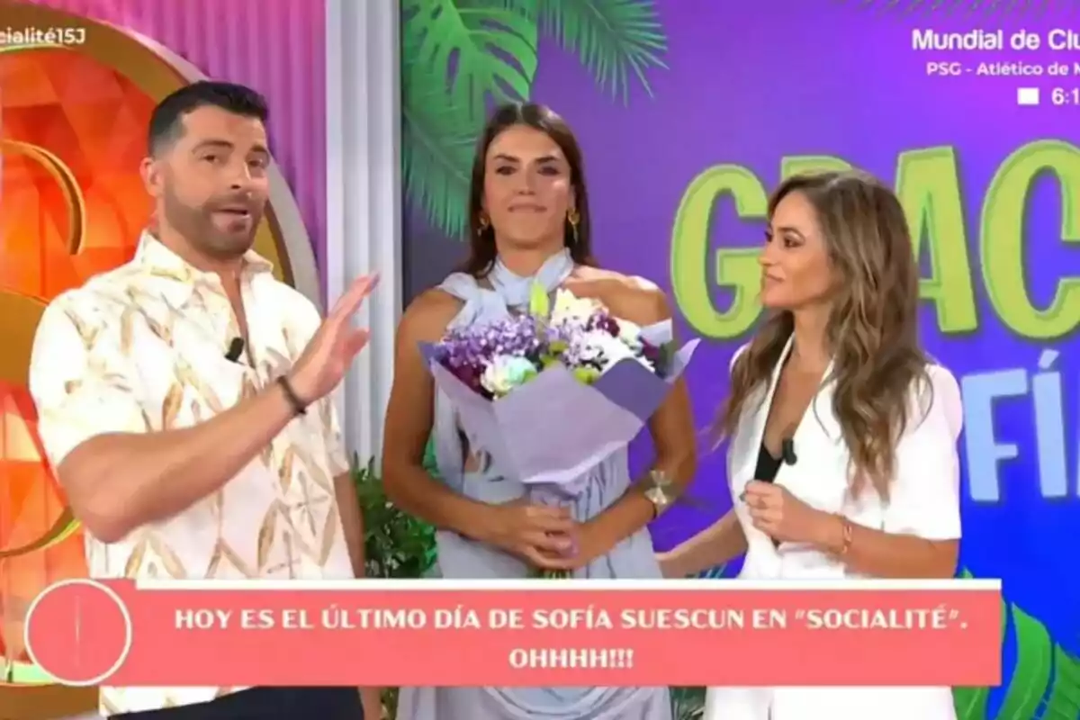 Antonio Santana, Sofía Suescun y María Verdoy personas en un set de Socialité colorido, una de ellas sostiene un ramo de flores y hay un mensaje en pantalla anunciando el último día de Sofía Suescun en el programa Socialité