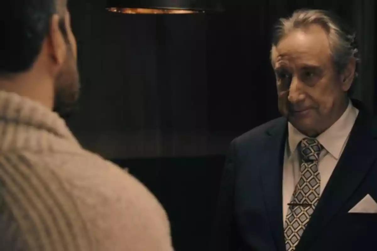 Don Pedro y Andrés conversan en una habitación con iluminación tenue, uno de ellos lleva un traje oscuro y corbata. Captura de 'Sueños de libertad' Don Pedro y Andrés conversan en una habitación con iluminación tenue, uno de ellos lleva un traje oscuro y corbata. Captura de 'Sueños de libertad'