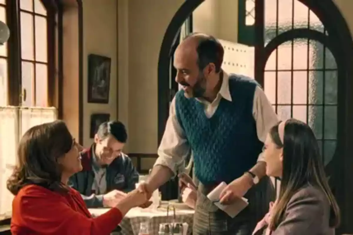 Gaspar somrient saluda a Manuela en un restaurant acollidor mentre Claudia observa l'escena. Captura de 'somnis de llibertat'. Gaspar somrient saluda a Manuela en un restaurant acollidor mentre Claudia observa l'escena. Captura de 'somnis de llibertat'.