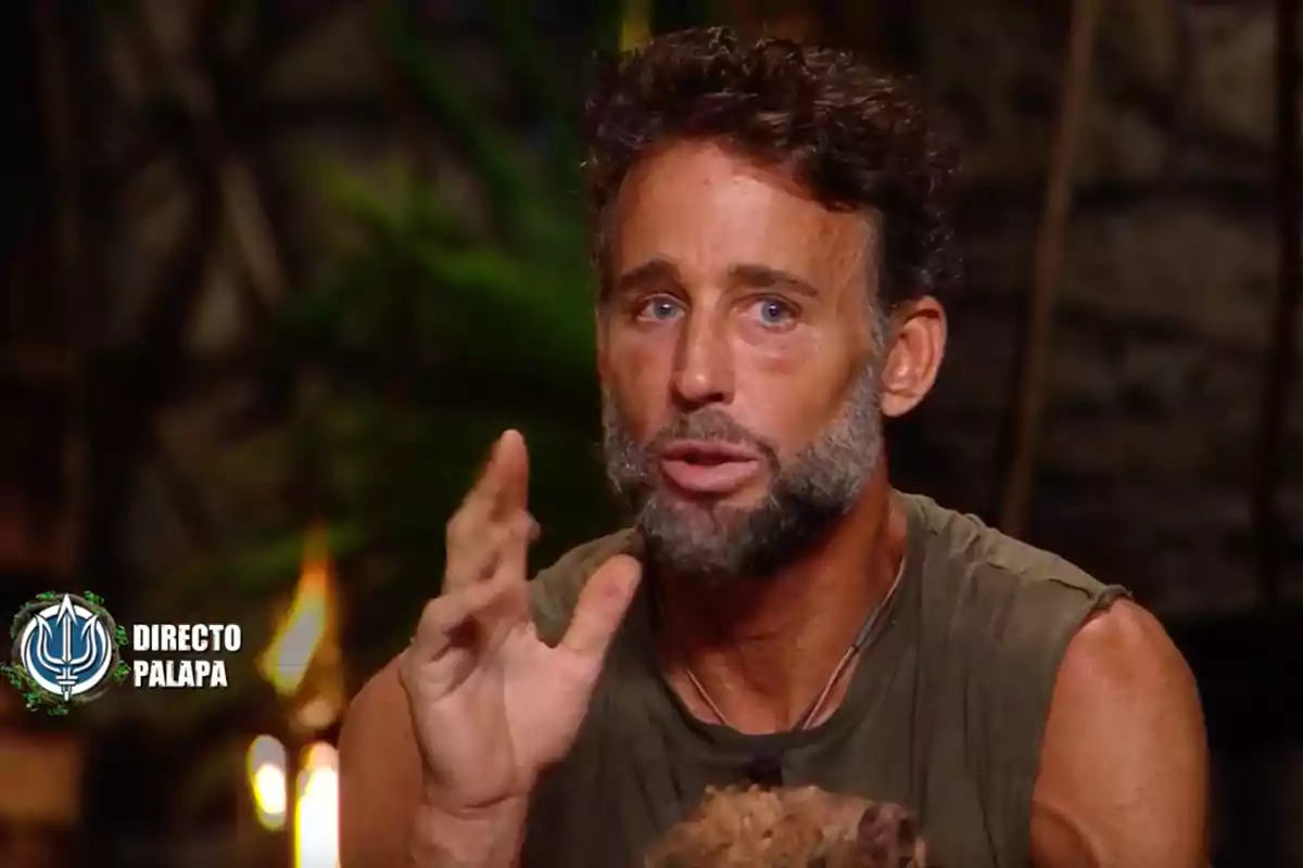 Álvaro Muñoz Escassi está hablando gesticulando con la mano en un entorno que parece una jungla o un set de televisión, con un logotipo en la esquina que dice "Directo Palapa". Captura de 'Supervivientes'