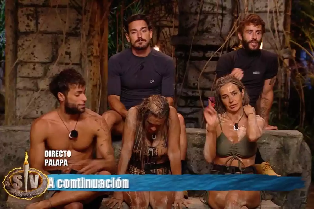 Un grupo de personas sentadas en un entorno al aire libre, algunas cubiertas de barro, con un letrero que dice Un grupo de personas sentadas en un entorno al aire libre, algunas cubiertas de barro, con un letrero que dice