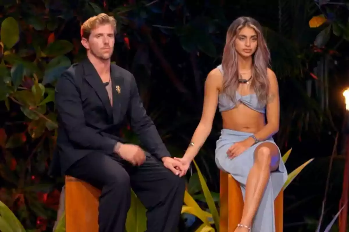 Tadeo y Sthefany sentados en un entorno tropical, ambos vestidos de manera elegante, sosteniéndose de la mano en La Isla de las Tentaciones. Tadeo y Sthefany sentados en un entorno tropical, ambos vestidos de manera elegante, sosteniéndose de la mano en La Isla de las Tentaciones.