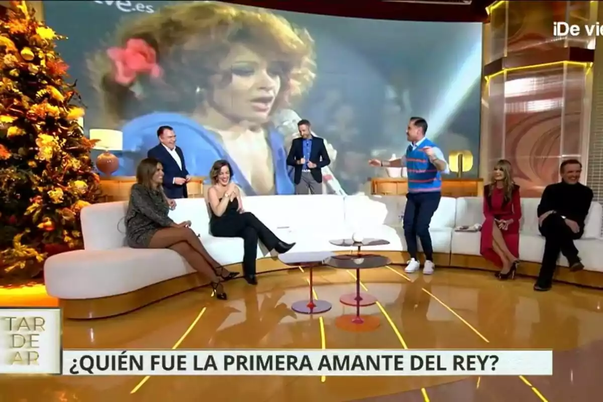 Un grupo de personas como Juan Luis Galiacho, Frank Blanco, Marta López, Leticia Requejo, Miguel Ángel Nicolás, Marisa Martín Blázquez y Antonio Montero está sentado en el plató de TardeAR decorado con un árbol de Navidad, mientras en la pantalla se proyecta la imagen de una mujer cantando. Un grupo de personas como Juan Luis Galiacho, Frank Blanco, Marta López, Leticia Requejo, Miguel Ángel Nicolás, Marisa Martín Blázquez y Antonio Montero está sentado en el plató de TardeAR decorado con un árbol de Navidad, mientras en la pantalla se proyecta la imagen de una mujer cantando.
