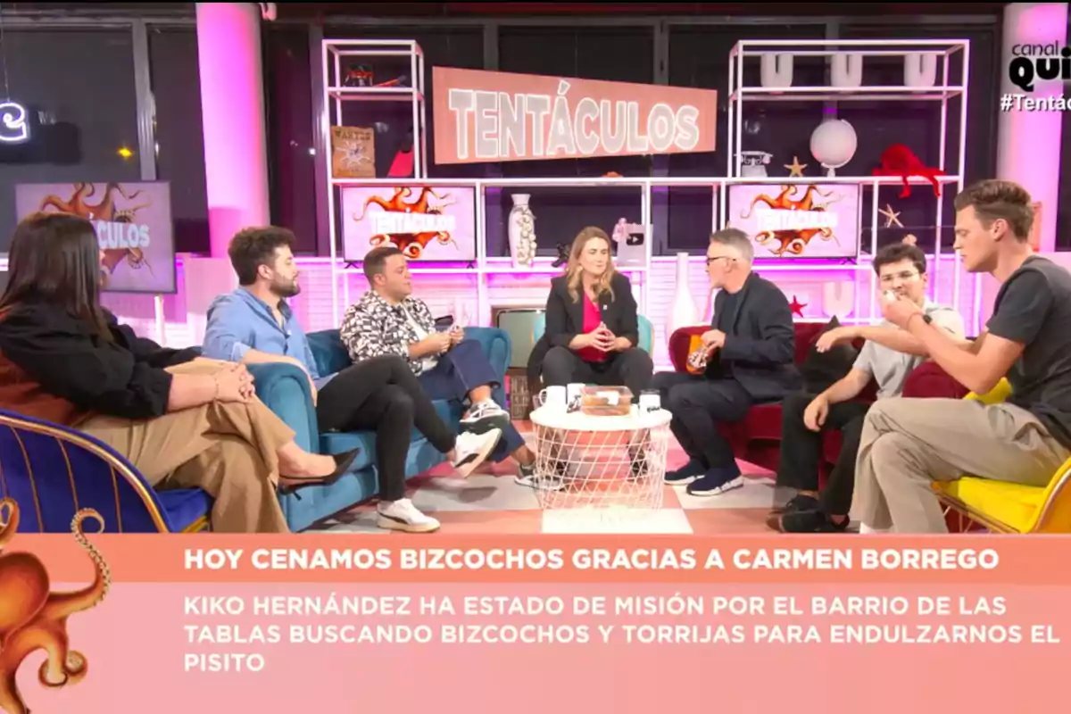 Un grup de persones assegudes en un plató de televisió acolorit amb el rètol Un grup de persones assegudes en un plató de televisió acolorit amb el rètol
