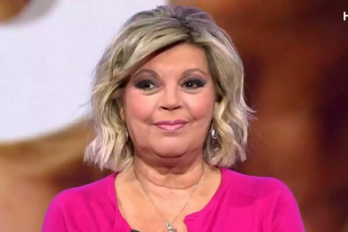Terelu Campos con cabello rubio y ondulado lleva una blusa rosa y está sonriendo frente a un fondo difuminado en De Viernes. Terelu Campos con cabello rubio y ondulado lleva una blusa rosa y está sonriendo frente a un fondo difuminado en De Viernes.