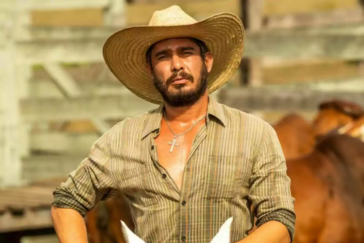 Fotografía de Tommy Schiavo con sombrero de paja y camisa a cuadros en un entorno rural con caballos al fondo. Fotografía de Tommy Schiavo con sombrero de paja y camisa a cuadros en un entorno rural con caballos al fondo.