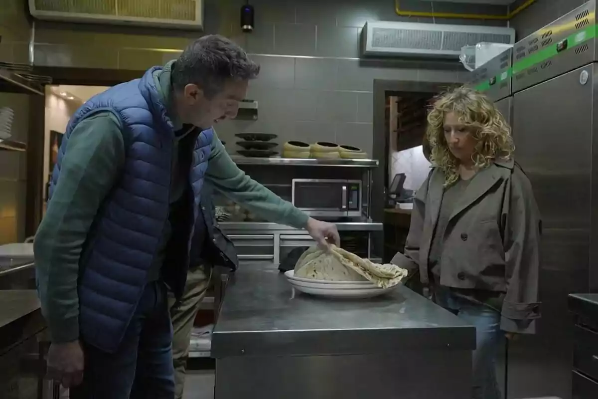 Dos personas en una cocina observan un plato con tortillas sobre una mesa de acero inoxidable en Batalla de Restaurantes. Dos personas en una cocina observan un plato con tortillas sobre una mesa de acero inoxidable en Batalla de Restaurantes.