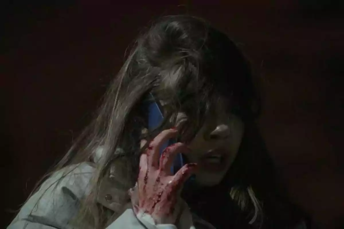 Umay con el cabello suelto habla por teléfono mientras su mano está cubierta de sangre en Renacer.