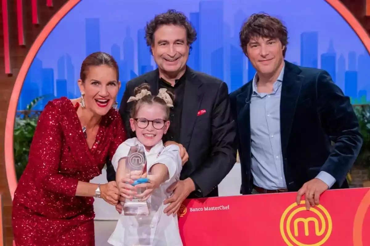 Jordi Cruz, Samantha Vallejo-Nágera i Pepe Rodríguez somriuen mentre Valentina sosté un trofeu de MasterChef Junior.